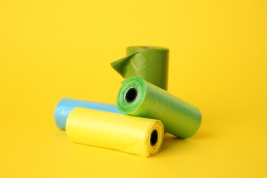 Photo of Colorful dog waste bags on yellow background