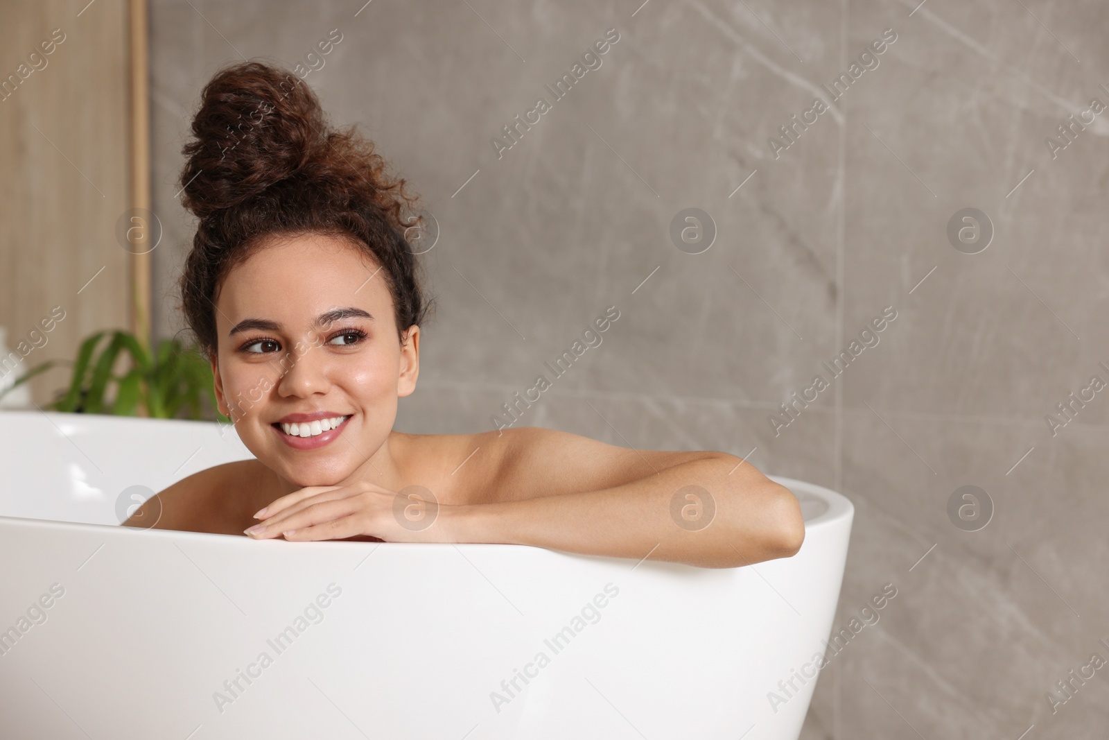 Photo of Beautiful African American woman taking bath indoors, space for text