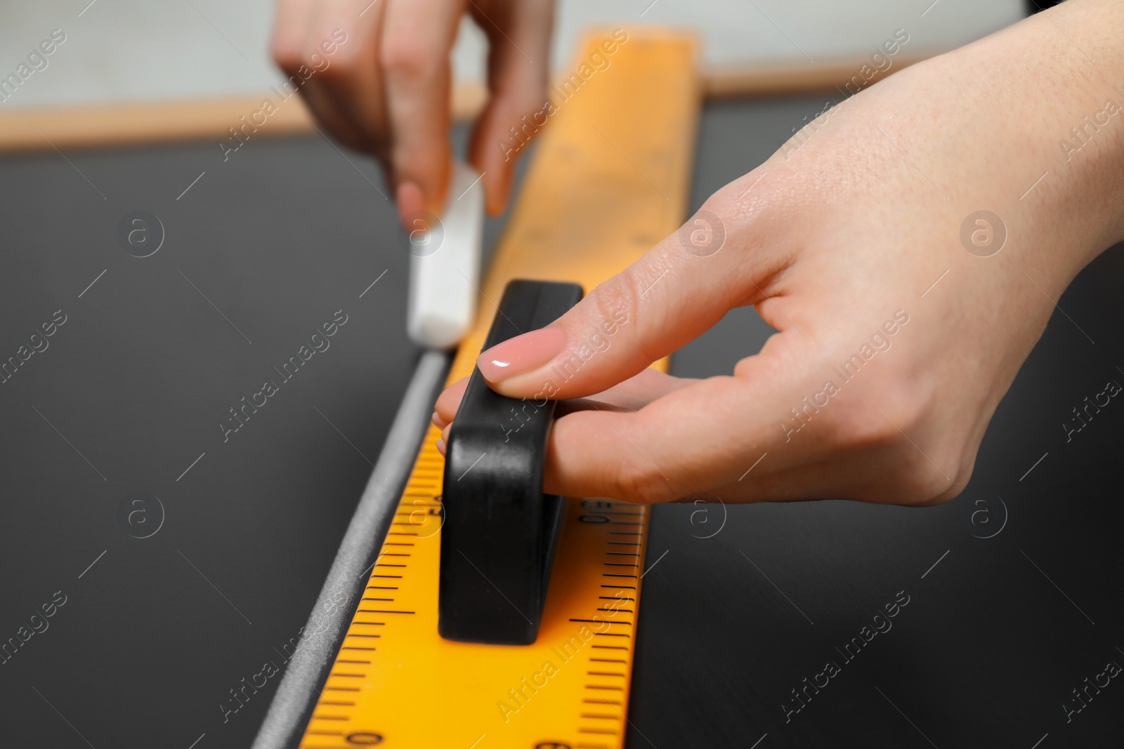 Photo of Woman drawing with chalk and triangle ruler on blackboard, closeup