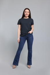 Young woman in stylish jeans on grey background