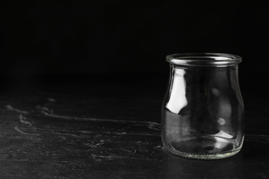 Empty glass jar on black stone table, space for text