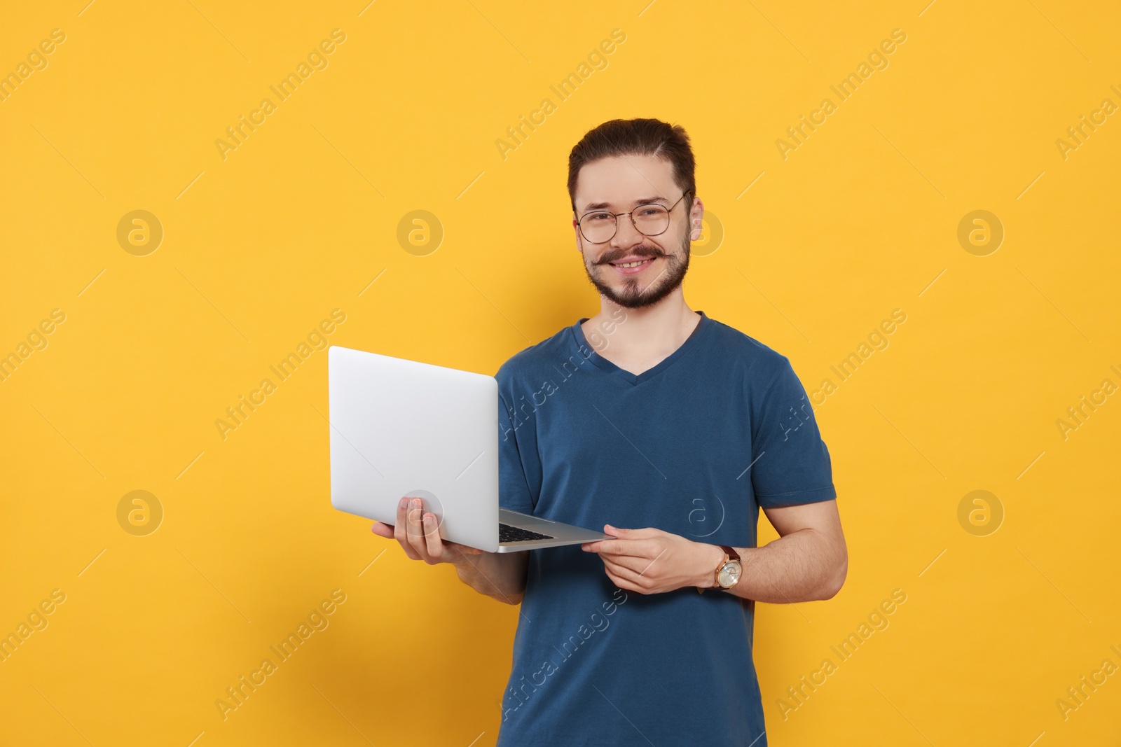 Photo of Happy man with laptop on orange background