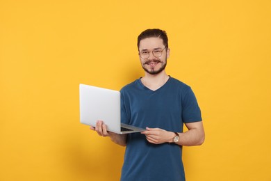 Happy man with laptop on orange background