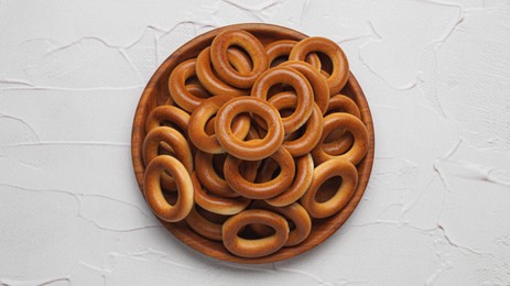 Photo of Bowl of tasty dry bagels (sushki) on white textured background, top view