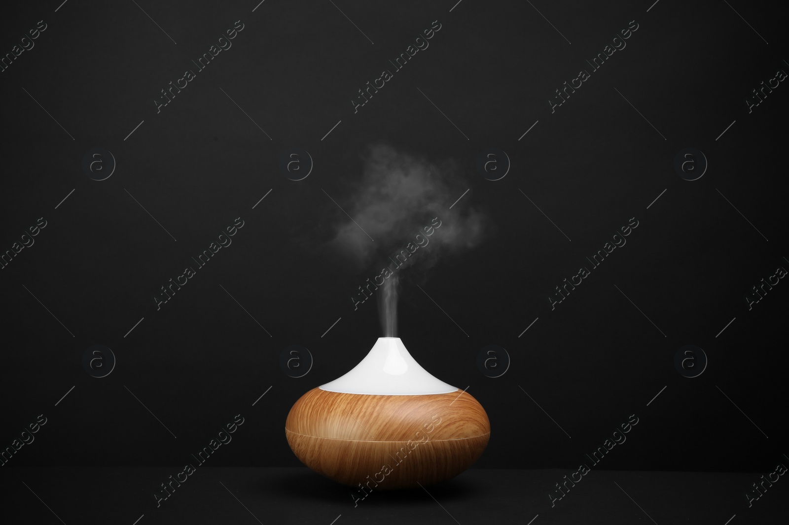 Photo of Modern essential oil diffuser on black background. Space for text