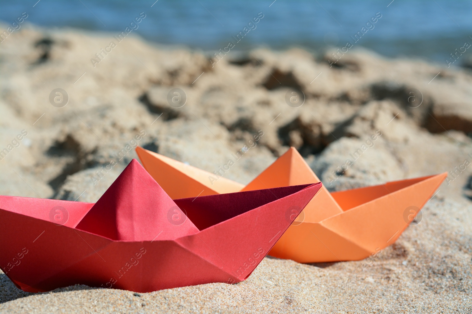 Photo of Two paper boats near sea on sunny day, closeup