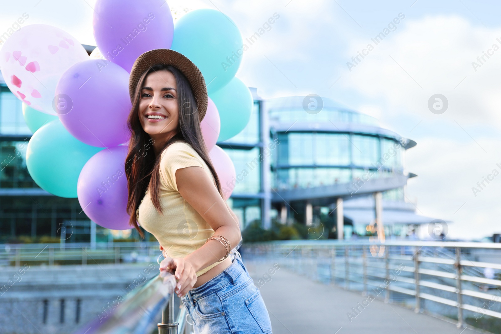 Photo of Beautiful young woman with color balloons on city street