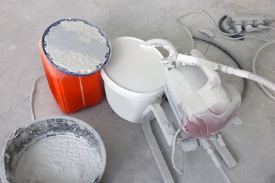 Photo of Sprayer and white paint on dirty floor