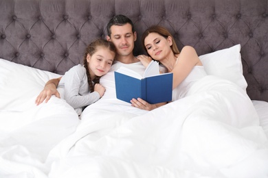 Happy family reading book with child in bedroom