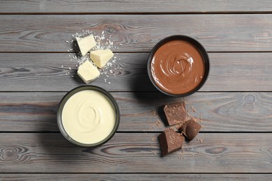 Photo of Tasty chocolate paste in bowls and pieces on wooden table, top view
