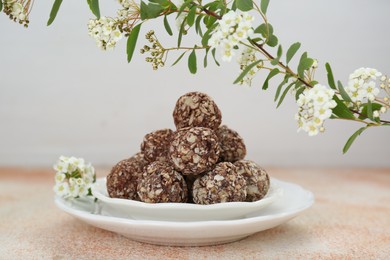 Delicious chocolate candies under blooming branch on beige table