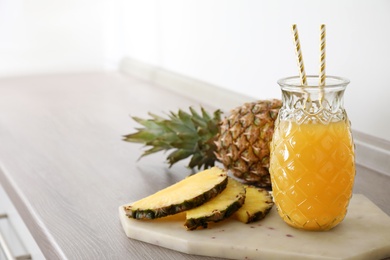 Photo of Delicious pineapple juice and fresh fruit on wooden table, space for text