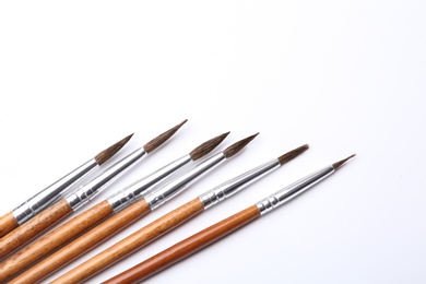 Photo of Different paint brushes on white background, top view