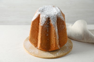Delicious Pandoro cake decorated with powdered sugar on white wooden table. Traditional Italian pastry