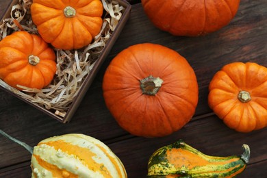 Photo of Crate and many different pumpkins on wooden table, flat lay