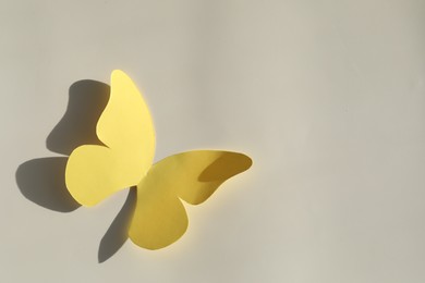 Photo of Yellow paper butterfly on light grey background, top view. Space for text