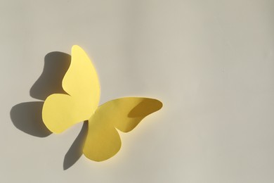 Yellow paper butterfly on light grey background, top view. Space for text