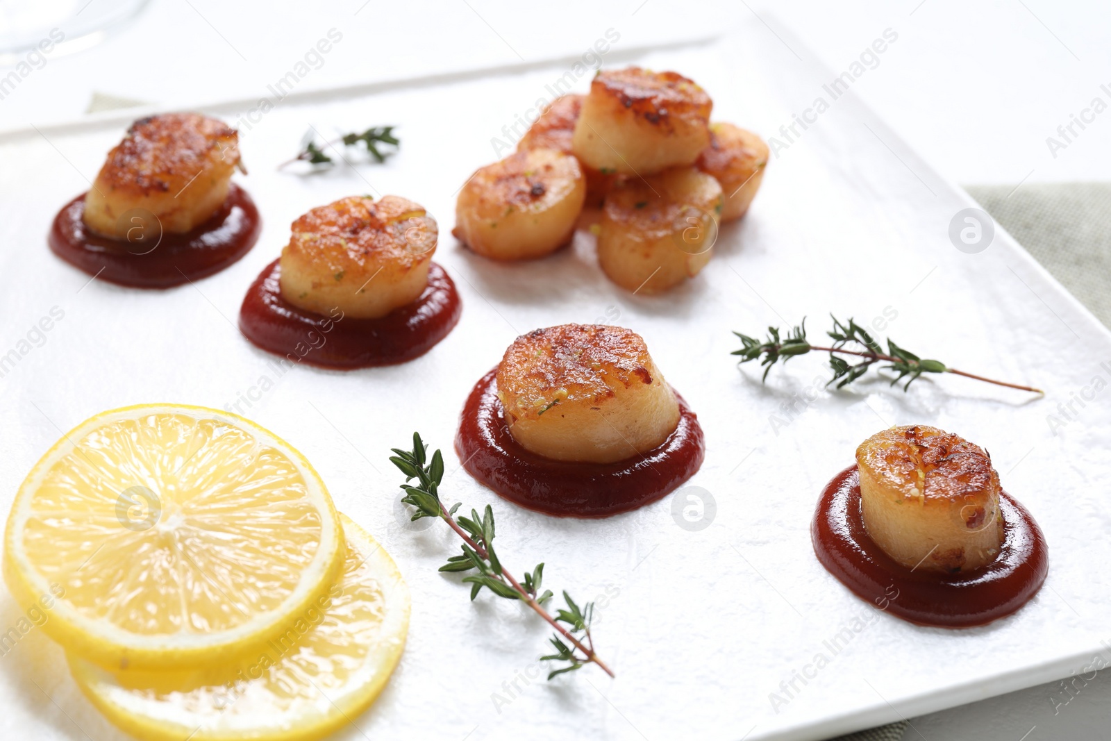 Photo of Delicious fried scallops with tomato sauce and lemon on table, closeup