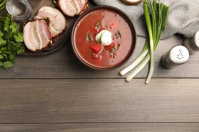 Photo of Clay bowl with Ukrainian borsch served on wooden table, flat lay. Space for text