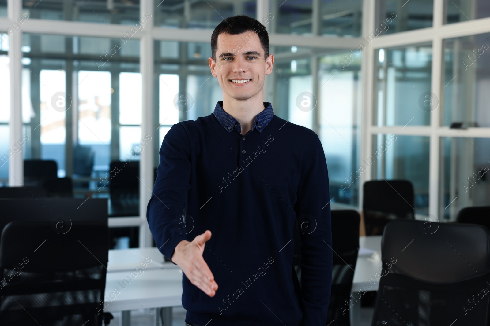 Photo of Happy man welcoming and offering handshake in office