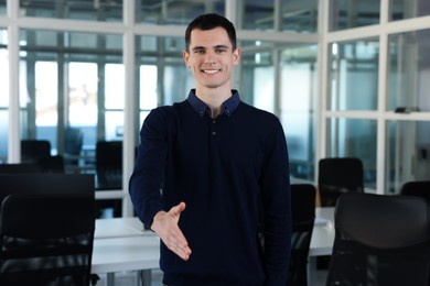 Happy man welcoming and offering handshake in office