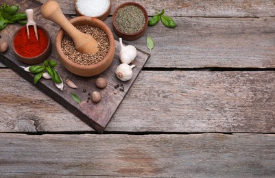 Photo of Mortar with pestle and different spices on wooden table, above view. Space for text