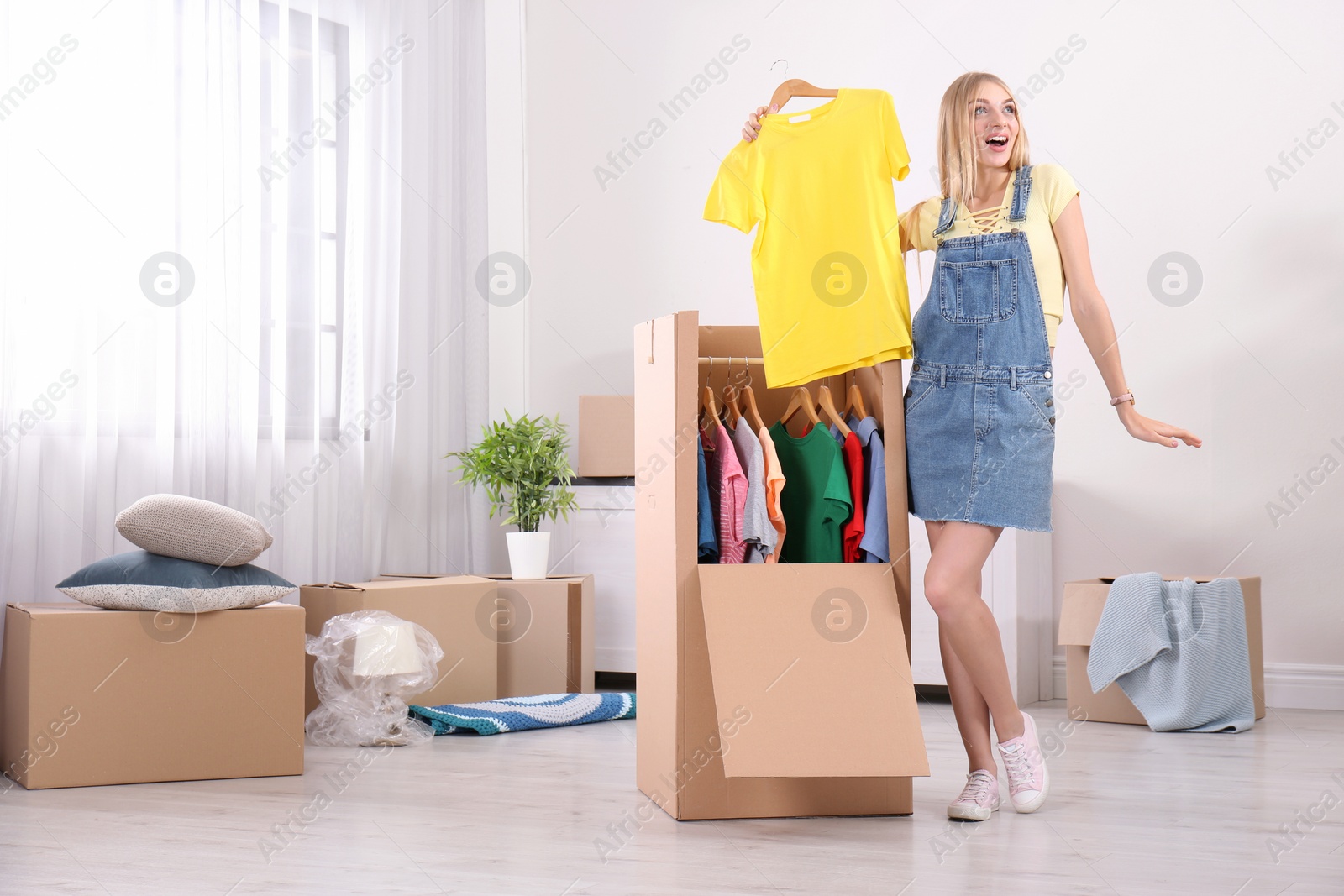 Photo of Young emotional woman near wardrobe box at home