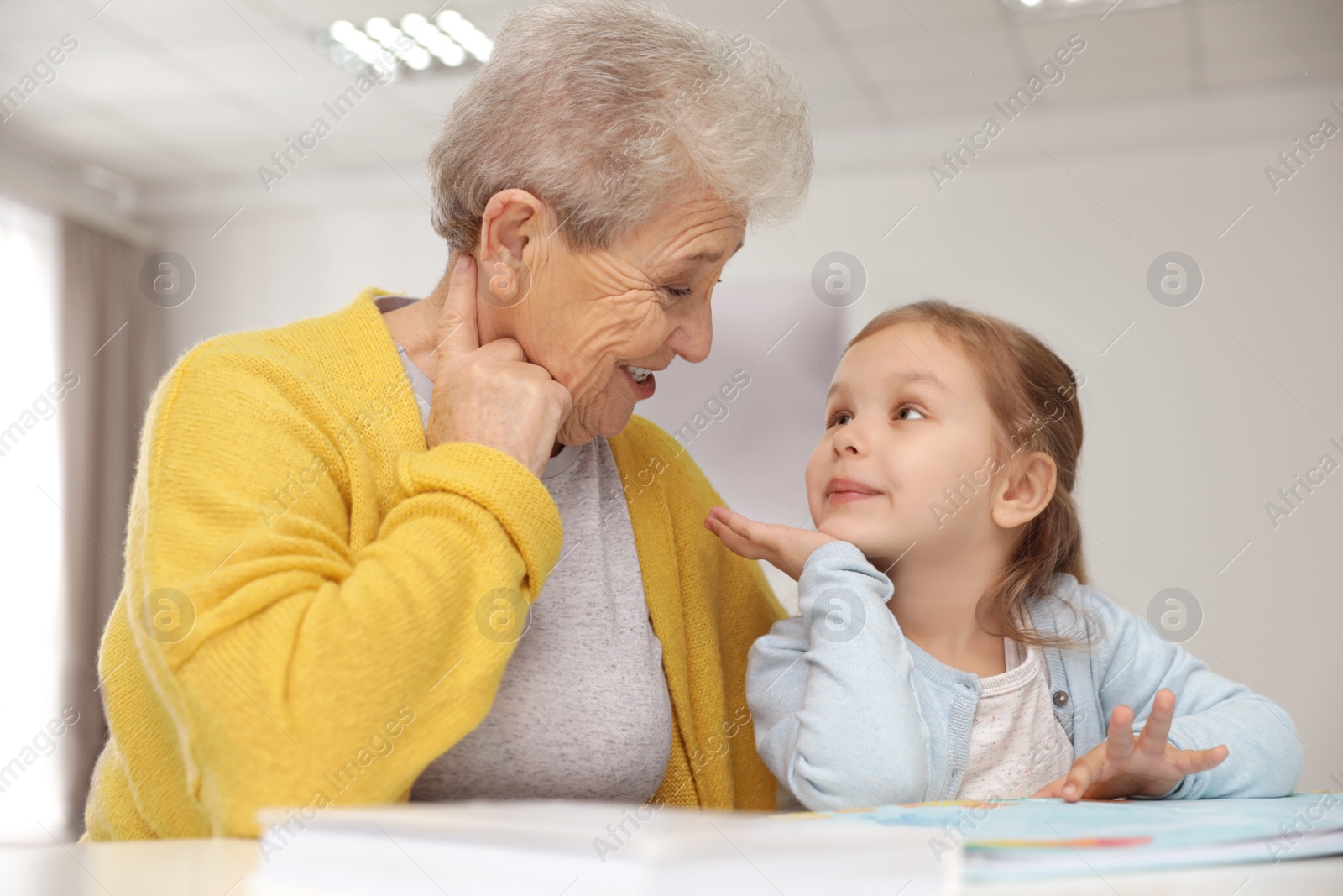 Photo of Cute girl and her grandmother reading book at home