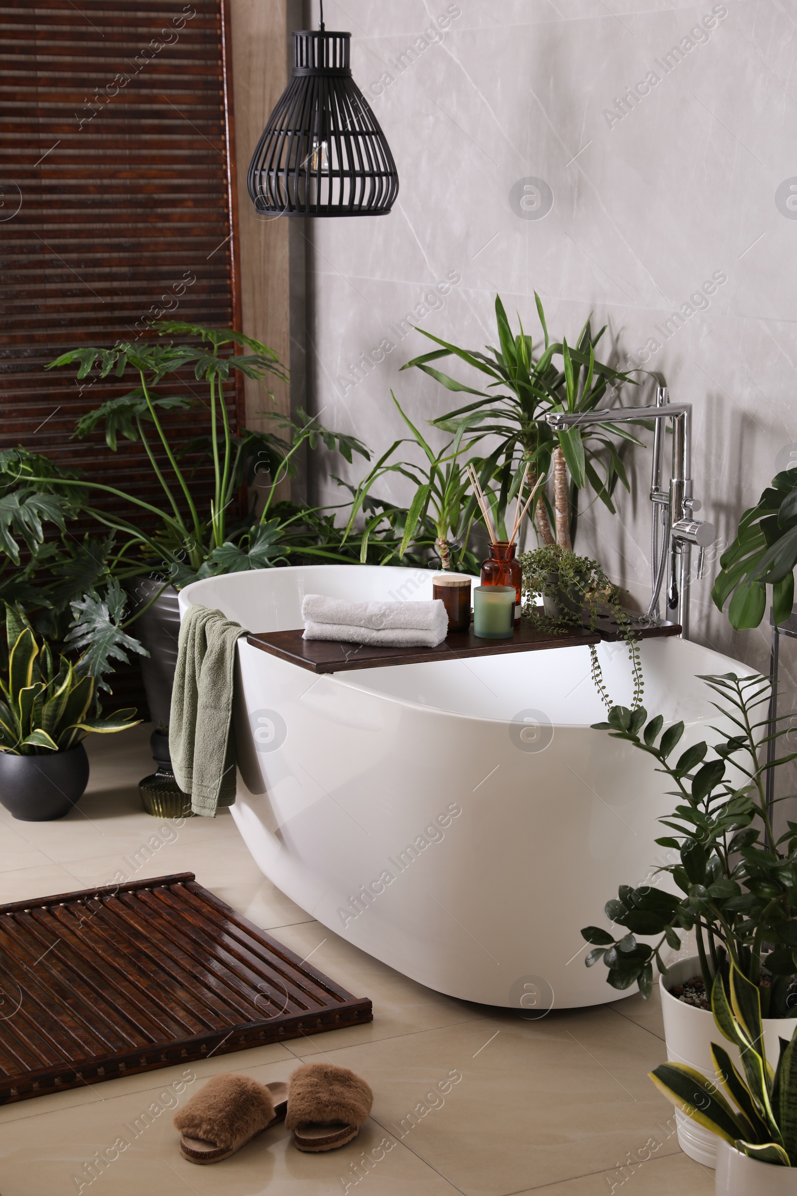 Photo of Modern white tub and beautiful green houseplants in bathroom. Interior design