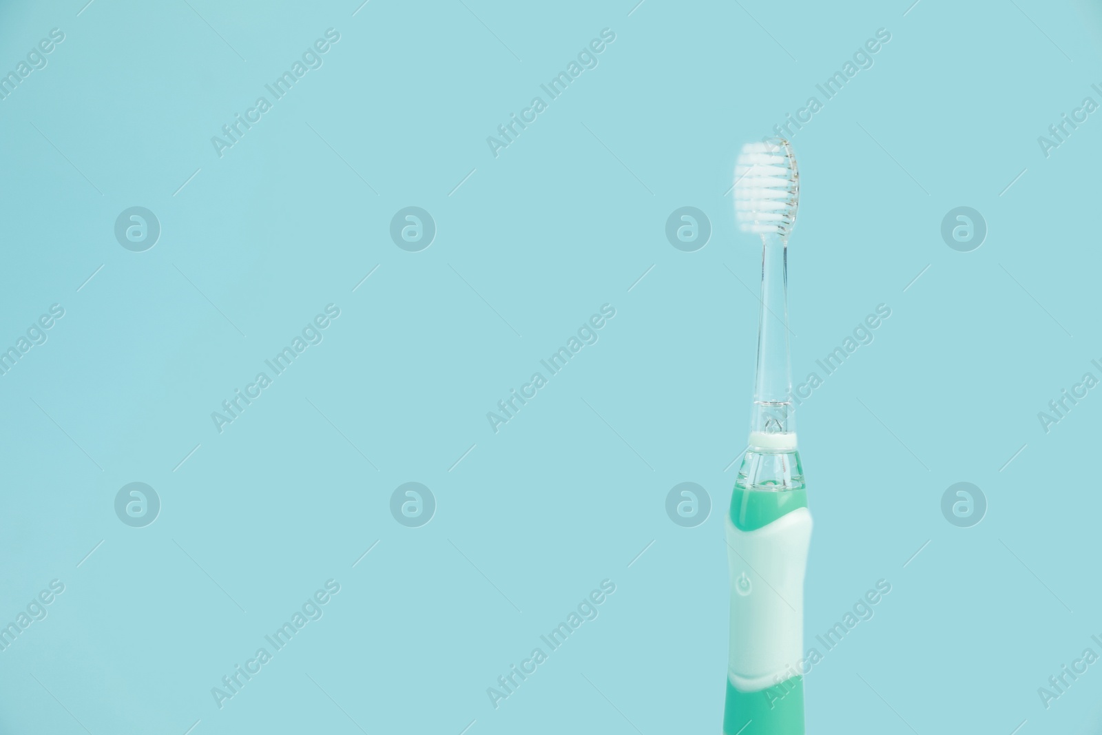 Photo of Electric toothbrush on light blue background, space for text