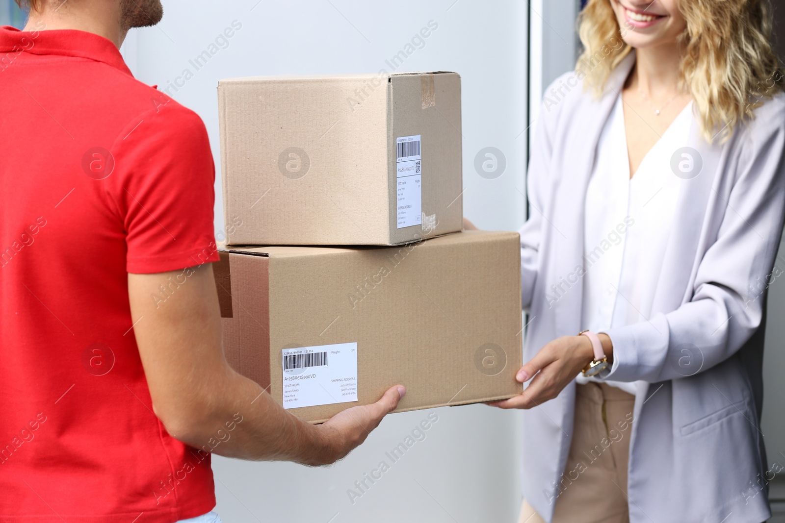 Photo of Young woman receiving parcels from courier on doorstep