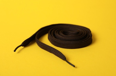 Rolled dark brown shoe lace on yellow background