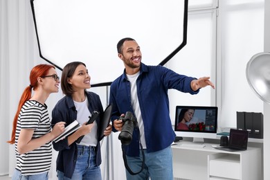 Photo of Young professional photographers working in modern photo studio, space for text