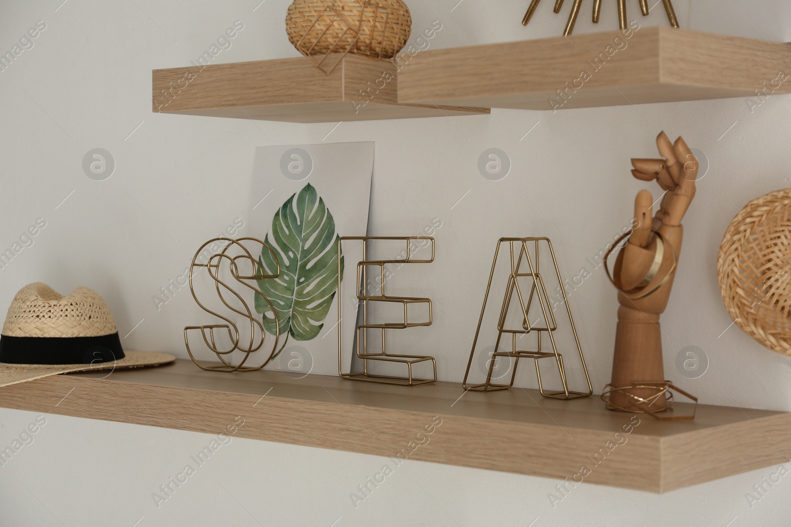 Photo of Wooden shelves with women's accessories and different decorative elements on light wall