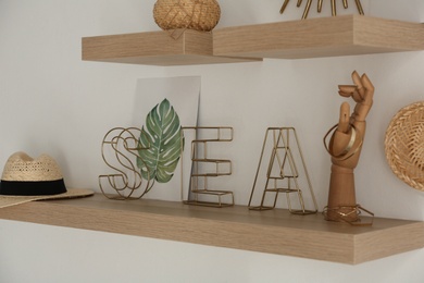 Wooden shelves with women's accessories and different decorative elements on light wall