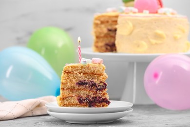 Piece of delicious cake with burning candle on light grey table, closeup