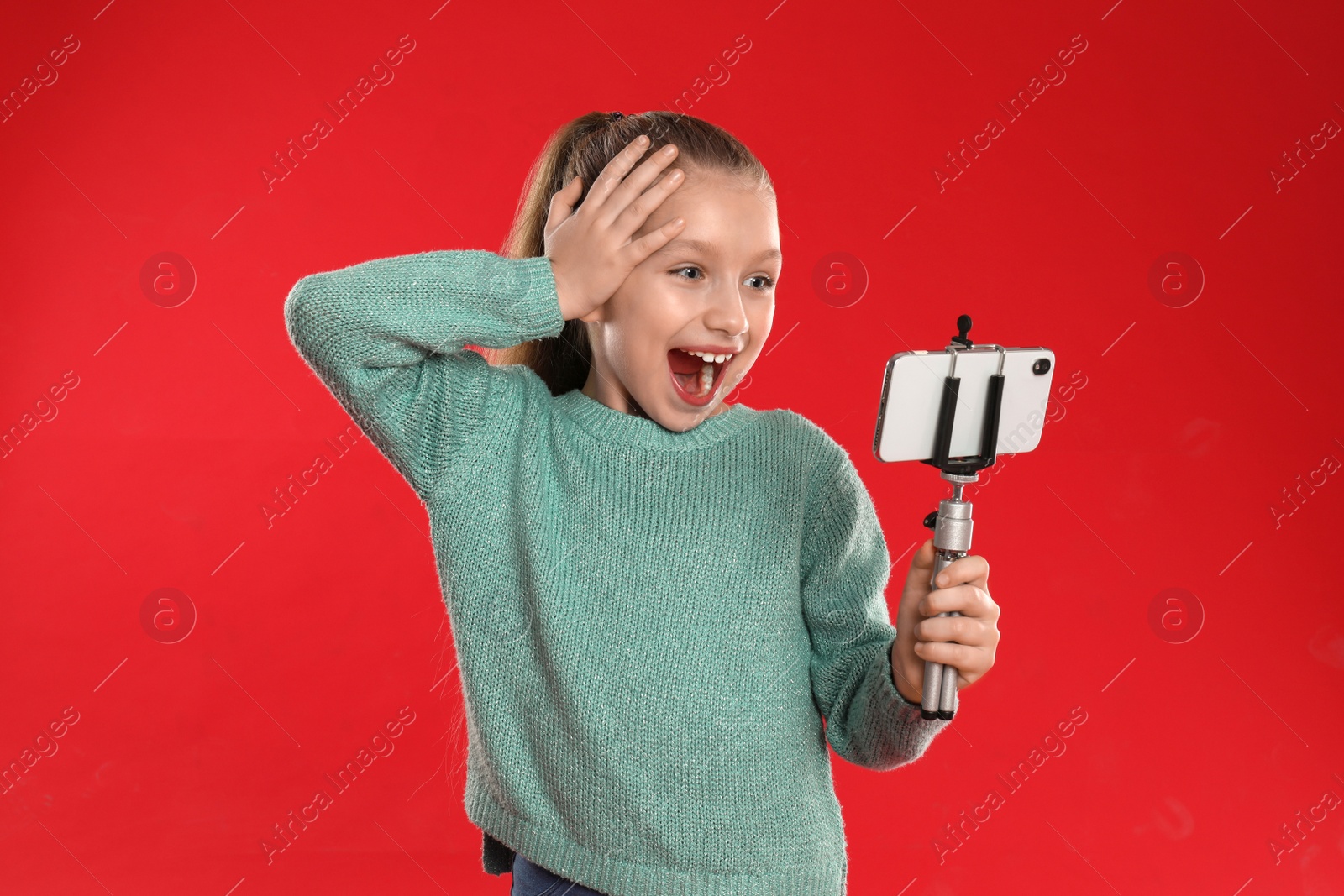 Photo of Excited little blogger recording video on red background
