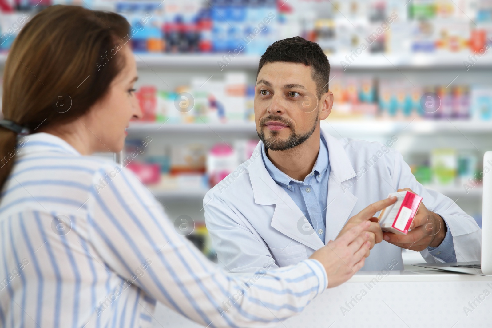 Photo of Professional pharmacist giving medicine to customer in drugstore