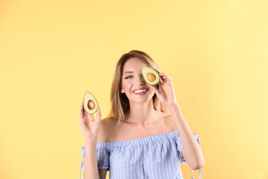 Portrait of young beautiful woman with ripe delicious avocado on color background