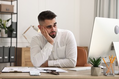 Photo of Overwhelmed man sitting at table in office