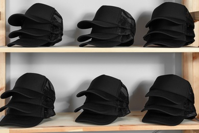 Photo of Blank black caps on wooden rack in store. Mock up for design