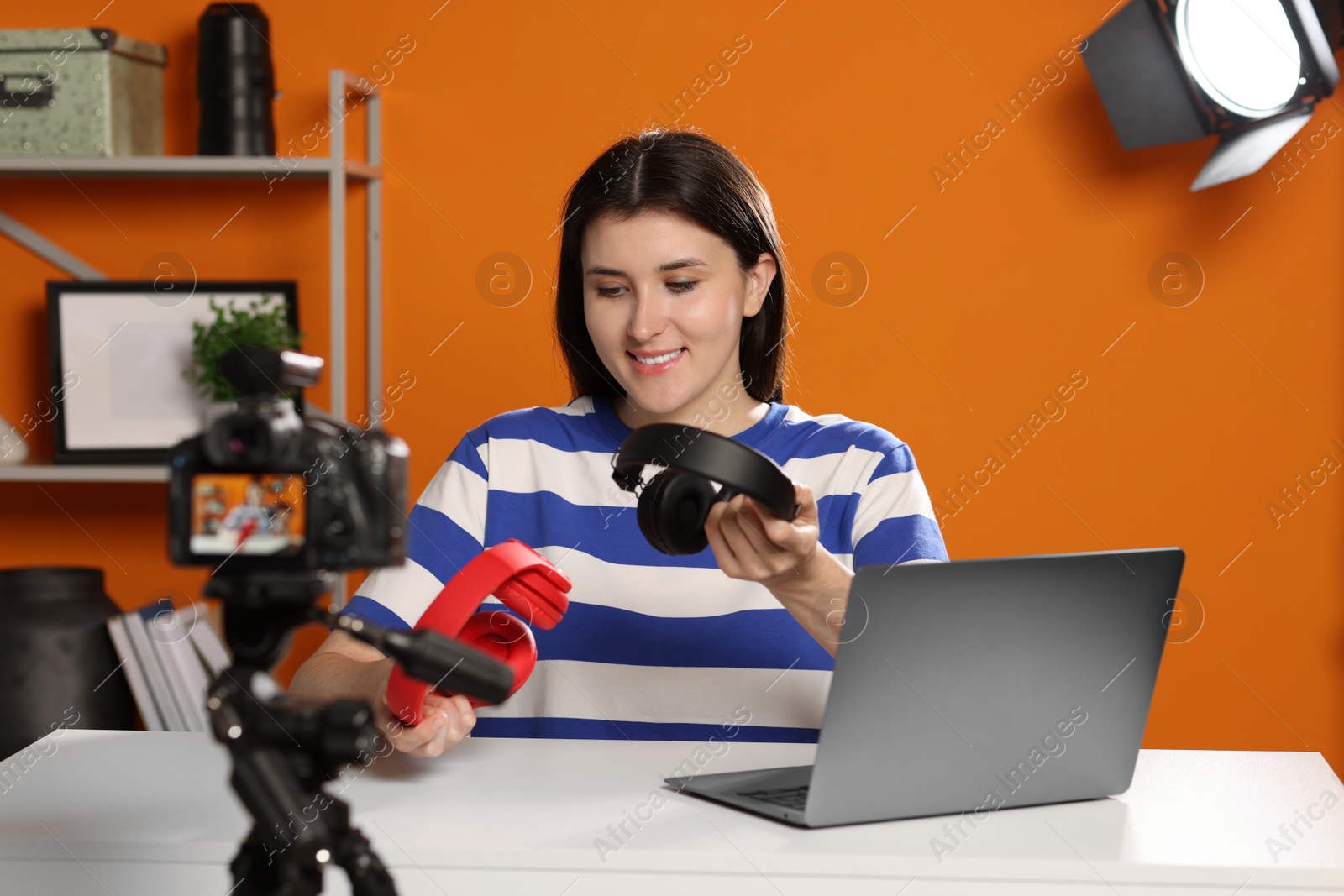 Photo of Smiling technology blogger recording video review about headphones at home