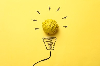 Photo of Idea concept. Light bulb made with crumpled paper and drawing on yellow background, top view