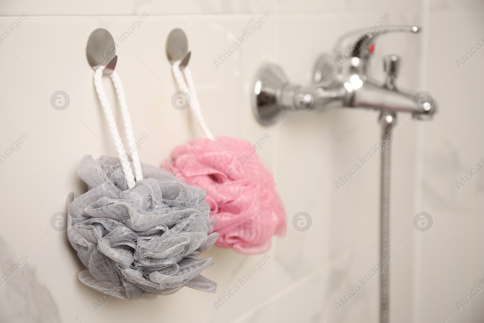 Photo of Shower puffs hanging near faucet in bathroom, space for text