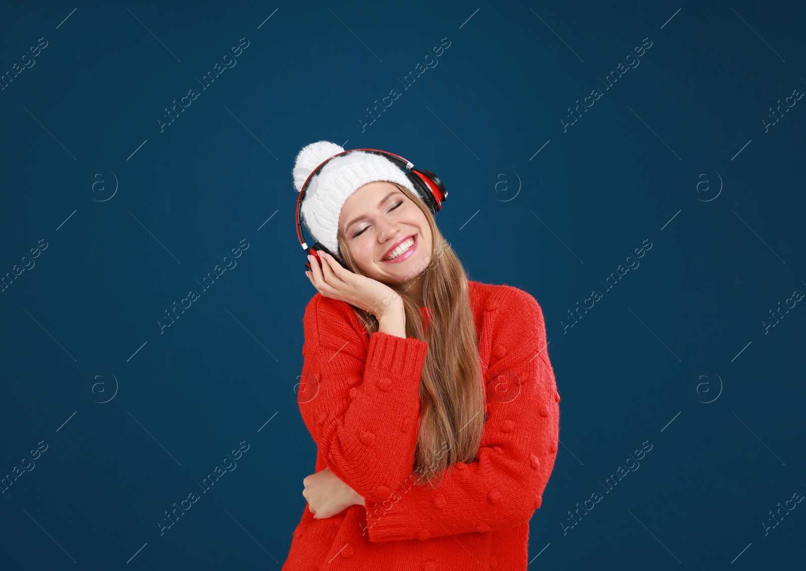 Photo of Young woman listening to music with headphones on dark blue background