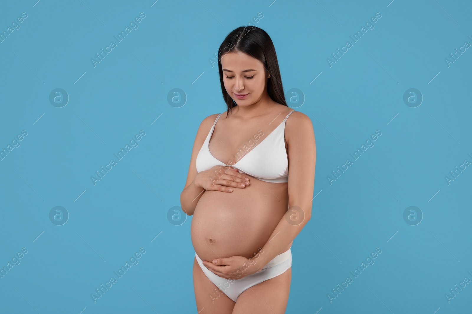 Photo of Beautiful pregnant woman in stylish comfortable underwear on light blue background