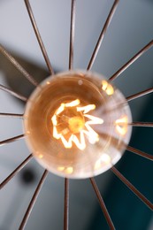 Photo of Stylish metallic pendant lamp with Edison light bulb indoors, bottom view