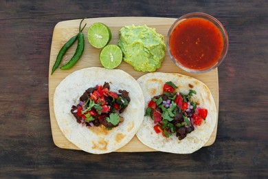 Photo of Delicious tacos and ingredients on wooden table, top view. Mexican food