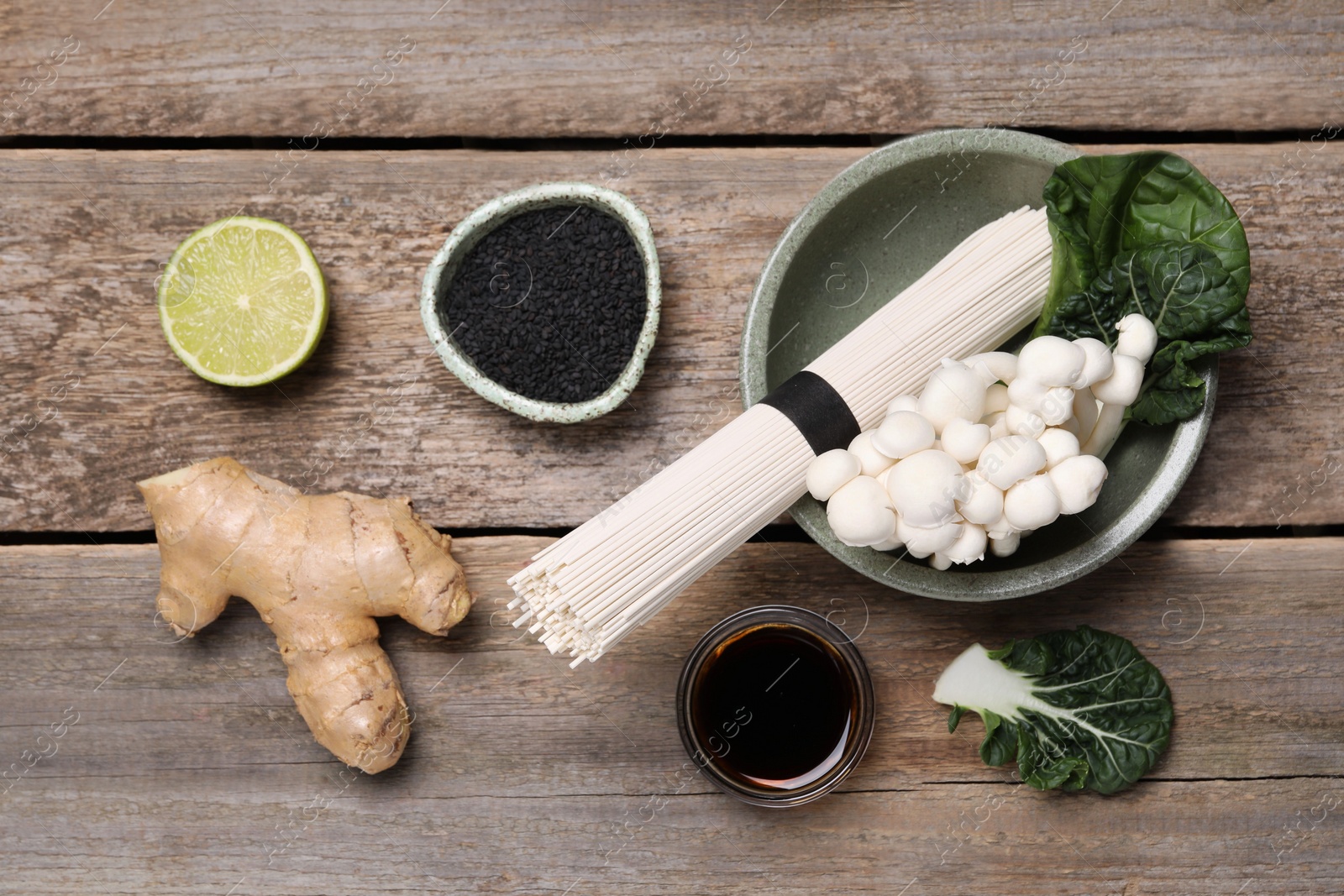 Photo of Cooking delicious ramen soup. Different ingredients on wooden table, flat lay