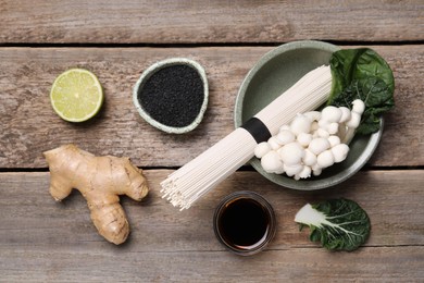 Photo of Cooking delicious ramen soup. Different ingredients on wooden table, flat lay